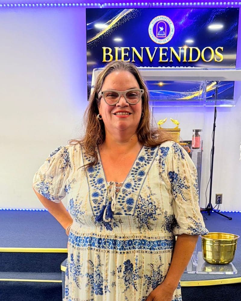 La pastora de misiones Wilnelia Castillo sonriendo frente al altar de la iglesia